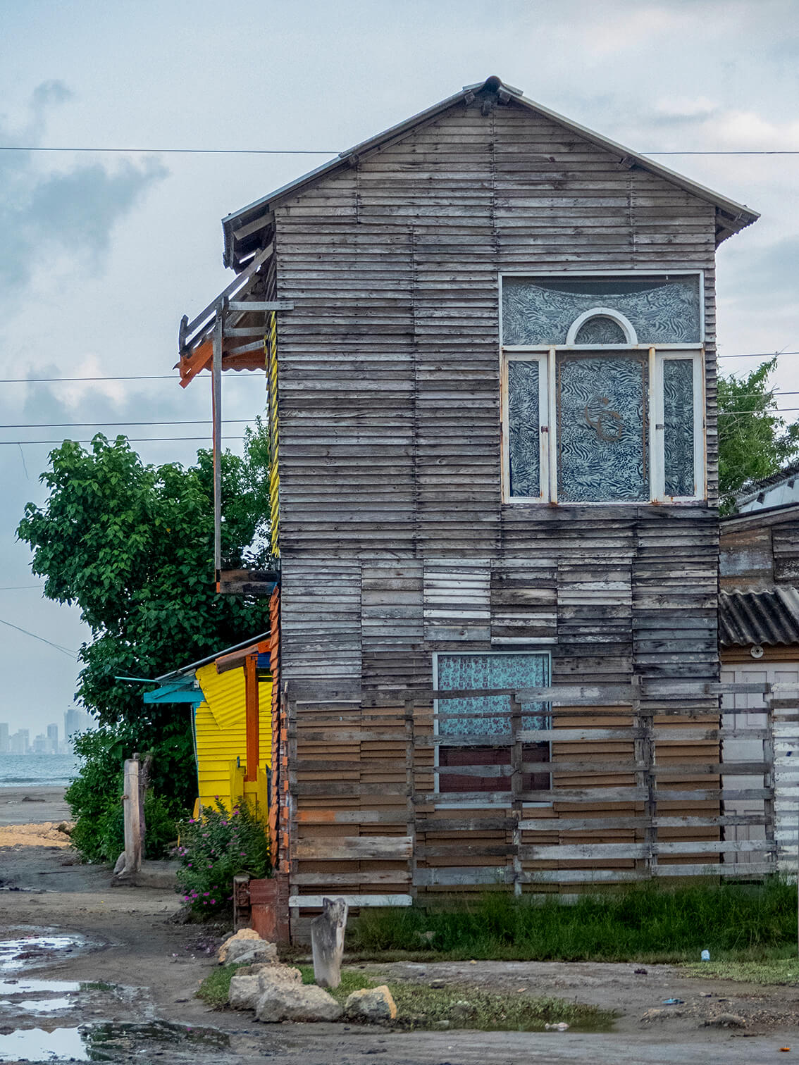 Dos casas de madera en La Boquilla, Cartagena, la comunidad que está cerca al mar. A lo lejos hay una cadena de hoteles.