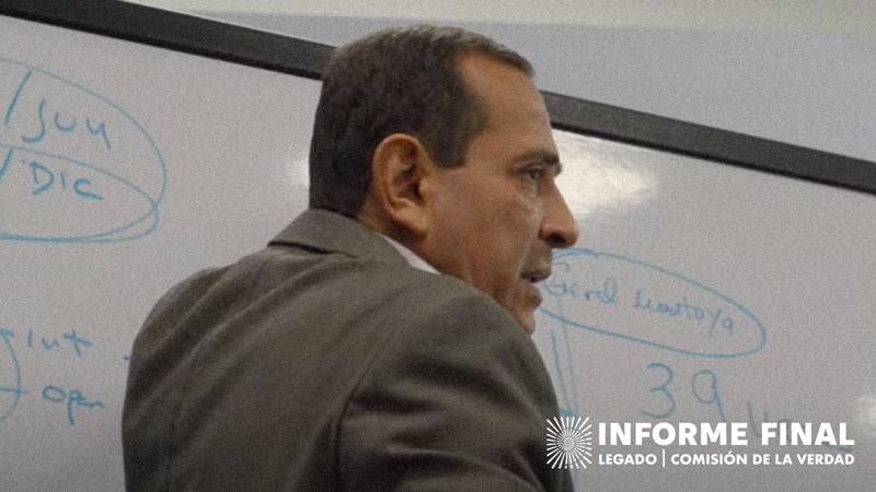 Luis Fernando Borja explica frente a un tablero acrílico con palabras escritas en el