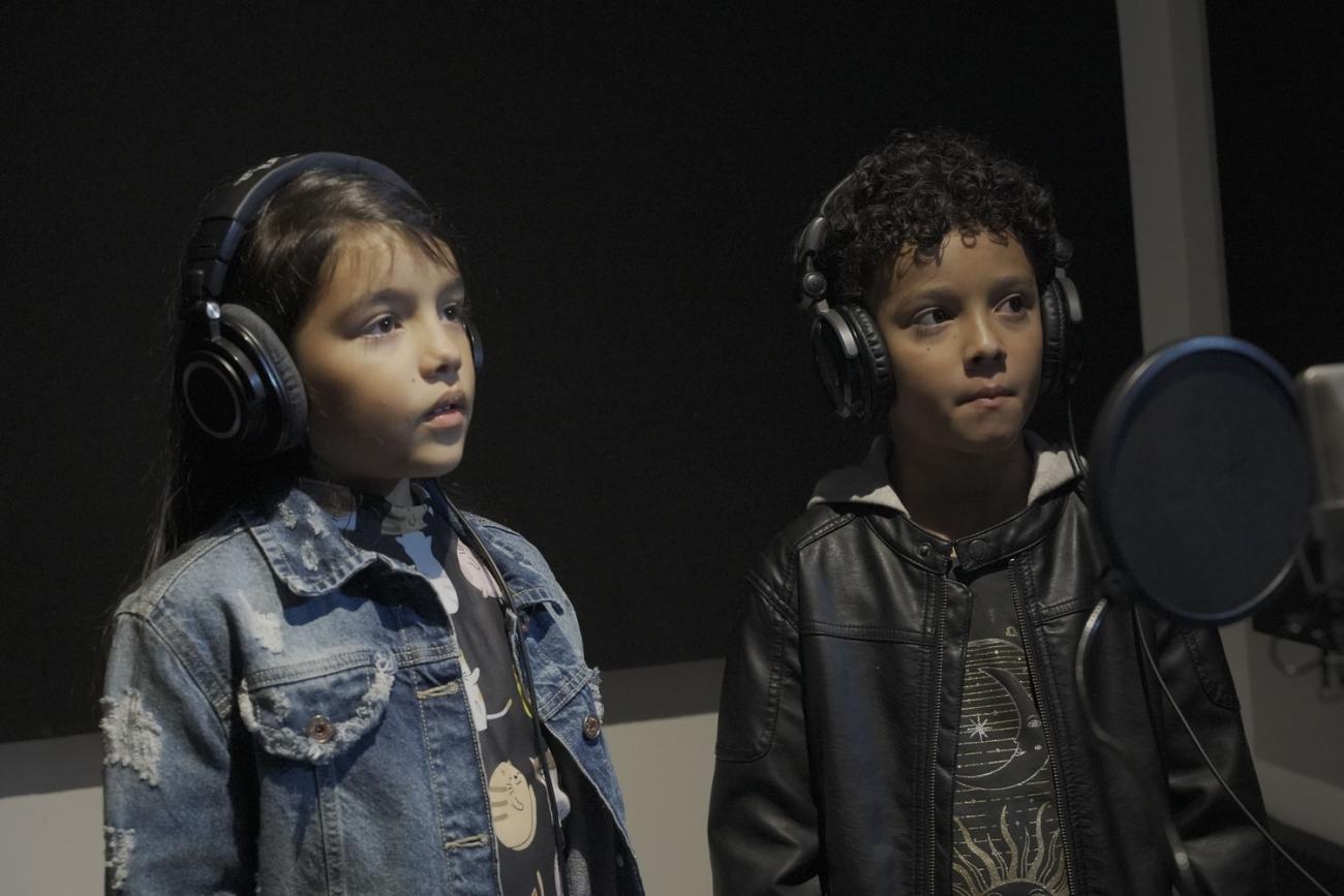 un niño y una niña cantando en un estudio de grabacion