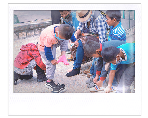 Instantánea. Grupo de  niños y una persona adulta se quitan los zapatos y las medias