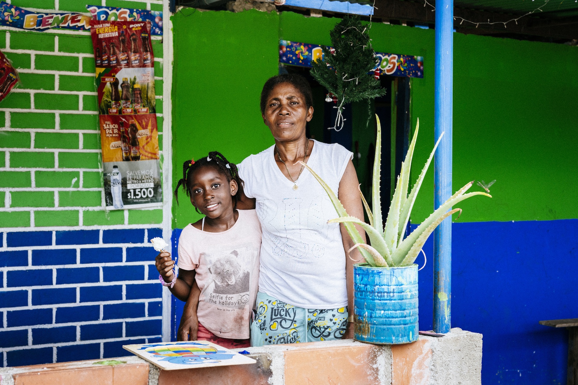 Frente a una tienda una mujer y una niña comen helado, se abrazan